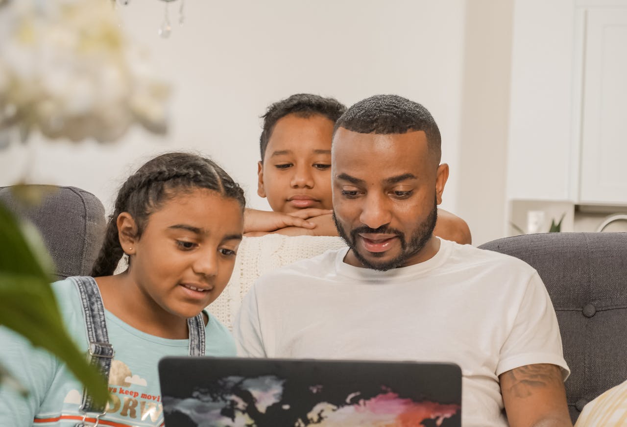 vision Father and children enjoying quality time together, using a laptop in a cozy setting.