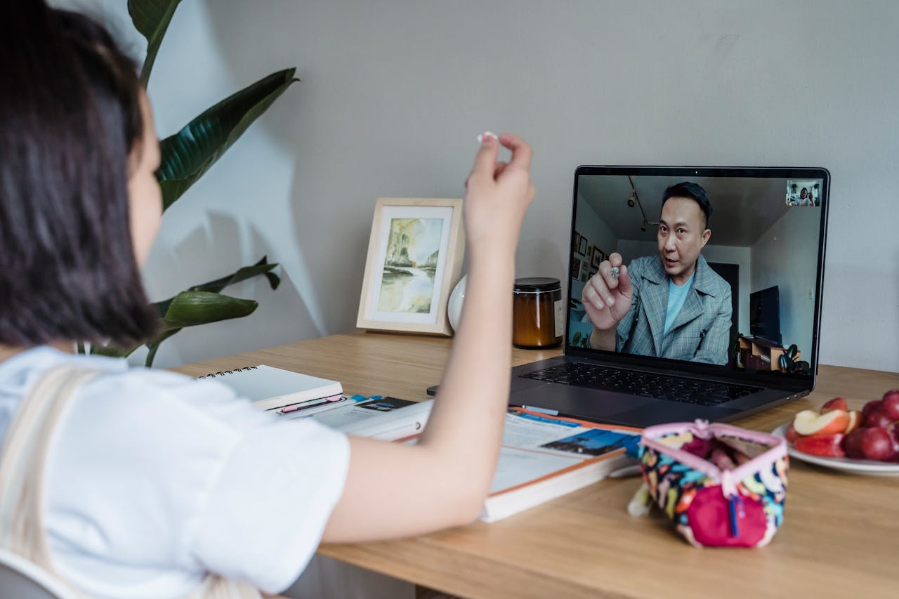 Child attends an online class with a teacher via video call on a laptop.